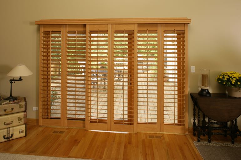 Wood shutters on sliding door connecting to outdoor porch.